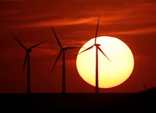 Three windmills and sun in the background