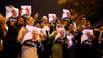 Iranians holding posters of President Hassan Rouhani as they welcome Iranian nuclear negotiators upo...