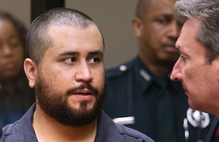 George Zimmerman in court looking at another man with police officers in the background 