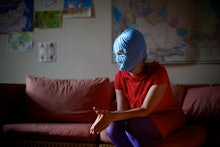 A member of the Russian punk group Pussy Riot wearing a blue mask and a red shirt while sitting on a...