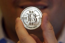 A man holding a silver printed out bitcoin