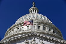 The United States Capitol with an american flag on a bright sunny day