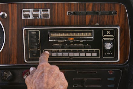 A person choosing their driving music on their car radio