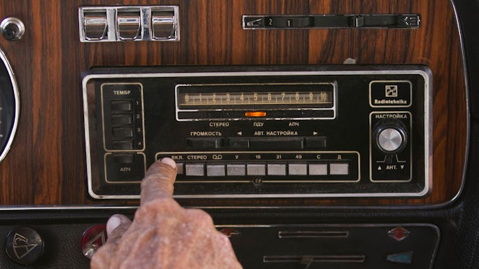 A person choosing their driving music on their car radio
