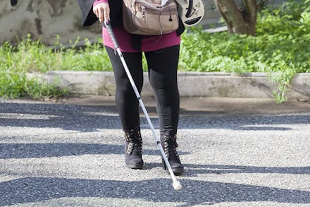 Visually impaired woman walking with the help of a stick