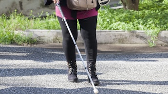 Visually impaired woman walking with the help of a stick