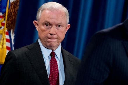Jeff Sessions staring at the camera while standing in front of an american flag