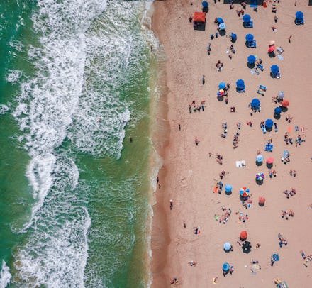 A crowded beach next to the sea from an aerial view