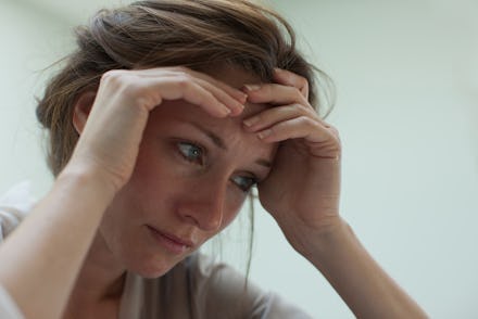 A depressed woman sitting and holding her head with her hands