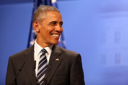 Barack Obama smiling in a black suit, a white shirt and black-and-white tie