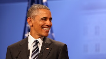 Barack Obama smiling in a black suit, a white shirt and black-and-white tie