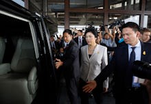 A member of Thailand's parliament entering a car with security men around her