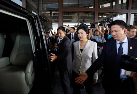 A member of Thailand's parliament entering a car with security men around her