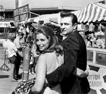 Johnny Cash hugging a woman as they walk through a fair 