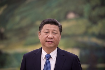 A portrait of Xi Jinping in a black suit, a white shirt, and a blue tie