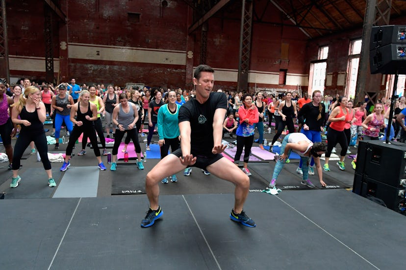 A man in front of a group of people during group exercise wearing Fitbit