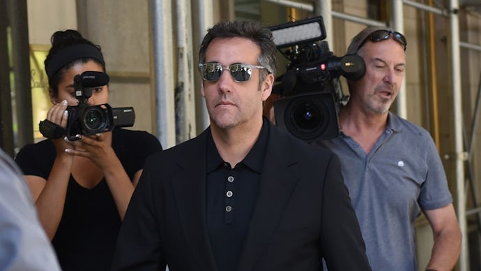 Michael Cohen wearing sunglasses with a people holding cameras walking behind him