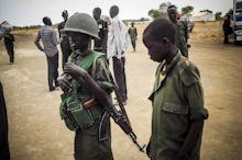 Two children and one of them is holding a helmet and a riffle in South Sudan