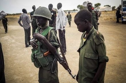 Two children and one of them is holding a helmet and a riffle in South Sudan