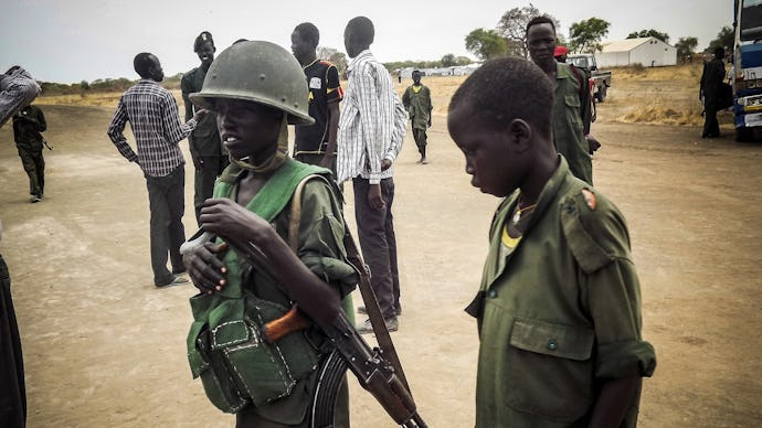 Two children and one of them is holding a helmet and a riffle in South Sudan