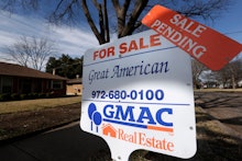 A for sale real estate wooden sign outside of a house