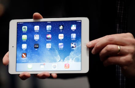 A person holding an iPad with a home screen opened