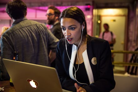 Alexandria Ocasio-Cortez  using a laptop and wearing white earphones
