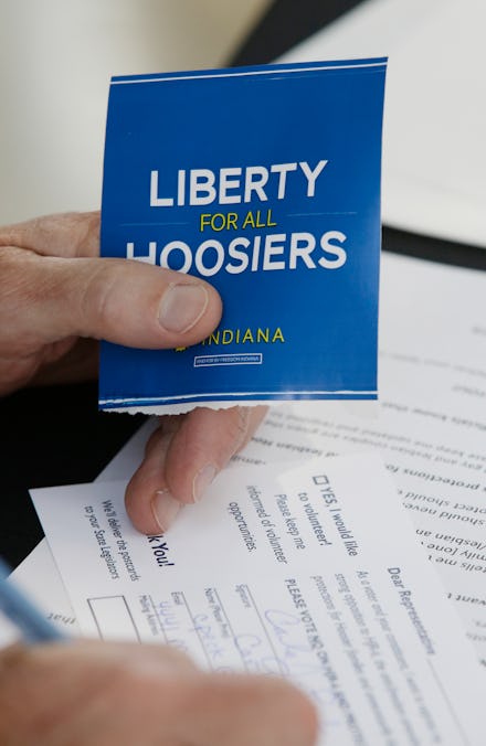 A man filling an application form and holding a "liberty for all hoosiers" paper
