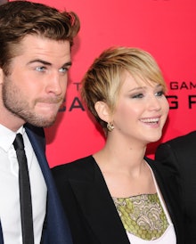 Jennifer Lawrence with a bob cut standing next to liam hemsworth at the red carpet premiere of the h...