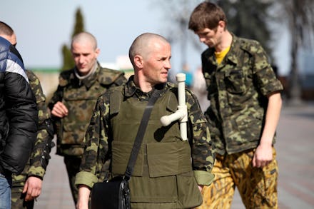 A group of Ukrainian protesters with homemade weapons walking down a street