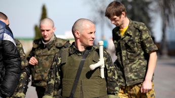 A group of Ukrainian protesters with homemade weapons walking down a street
