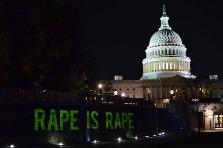 A sign that says rape is rape in front of the United States Capitol at night