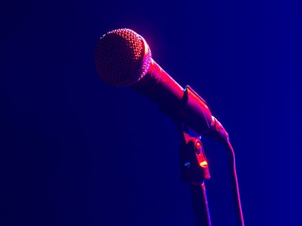 A microphone on stage lit by a spotlight