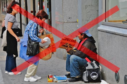 Red x sign over a homeless man sitting on a street