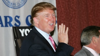 Donald Trump smiling and waving and journalists in a black suit, white shirt and a red tie