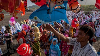 People celebrating Eid in a group while holding balloons
