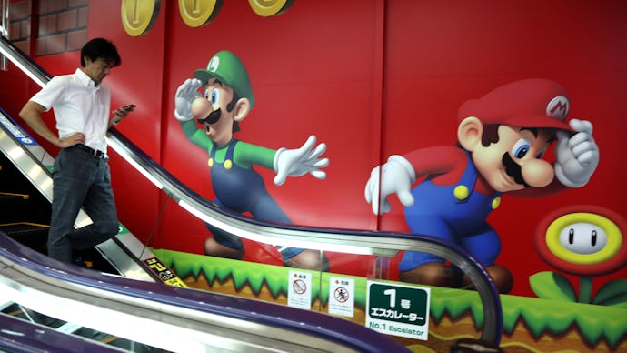 A man going down on escalator stairs with a large poster of Super Mario on a wall nest to the stairs