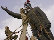 Soldiers putting an American flag over the head of a statue in Iraq