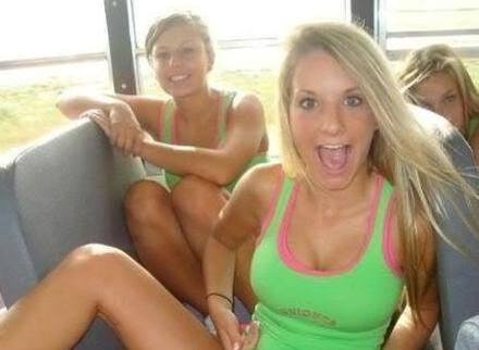 Three blonde women sitting in a car with grey seats and laughing