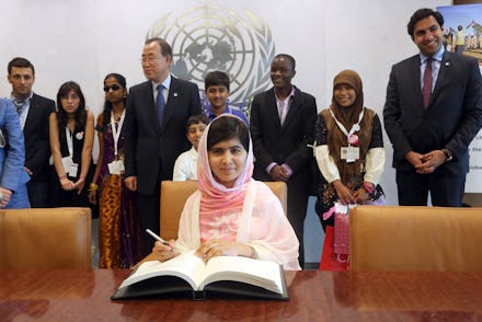 Malala Yousafzai sitting at the UN and writing in a book