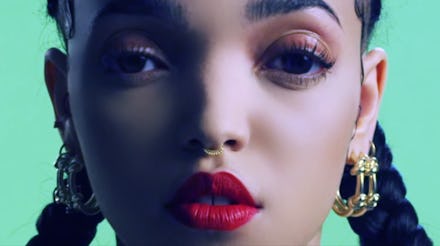 A closeup of FKA Twigs with a septum piercing and hoop earrings