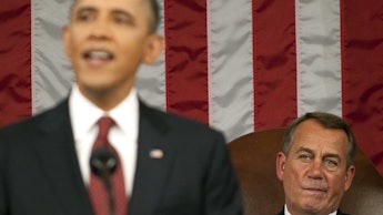 Barack Obama mid-sentence while giving a speech, with the American flag and another man in the back.