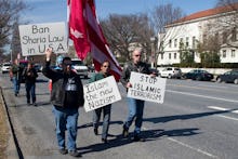 A group of people walking on a street with posters 'Ban Sharia Law in U.S.A.'