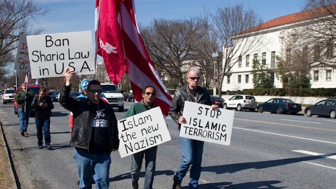 A group of people walking on a street with posters 'Ban Sharia Law in U.S.A.'
