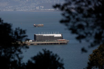 Google's Treasure Island Barge floating on the water seen from land between trees