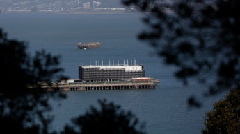 Google's Treasure Island Barge floating on the water seen from land between trees