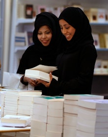 Saudi Girls studying Science looking at the book in a library
