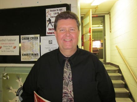 Patrick Jones in a black shirt and grey tie in a school hall