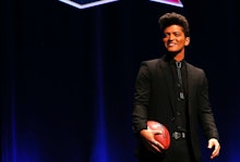 Bruno Mars standing on stage holding a football