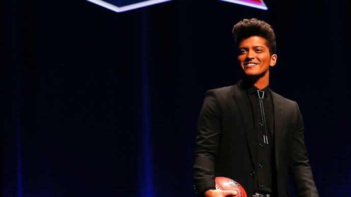 Bruno Mars standing on stage holding a football